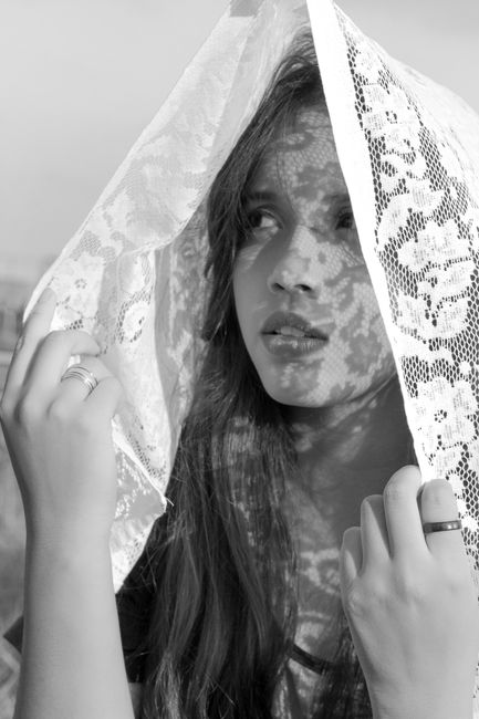 Artistic black and white portrait of a woman under a lace veil, capturing elegance and mystery.