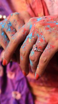 Close-up of vibrant Holi colors on hands adorned with a sparkling ring, capturing the festive spirit in Patna, India.