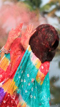 A colorful Holi celebration with a South Asian woman in Patna, India, covered in festive powder.