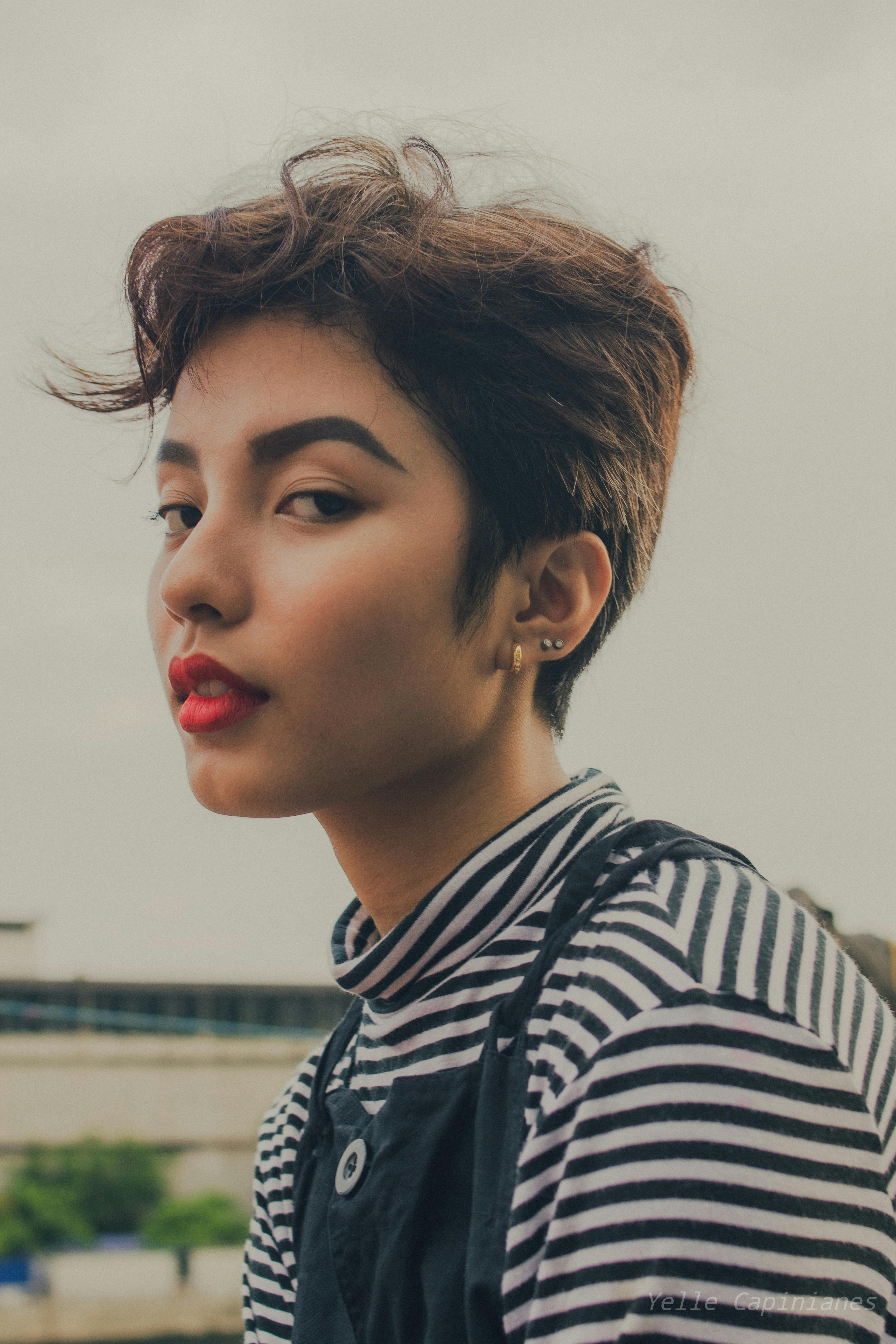 A captivating portrait of a woman with short hair and bold makeup, captured outdoors.