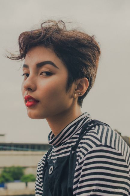 A captivating portrait of a woman with short hair and bold makeup, captured outdoors.