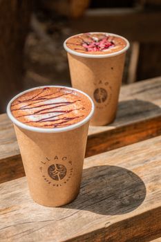 Two steaming cups of hot chocolate on a rustic bench, captured in the outdoors of Patagonia for a cozy vibe.