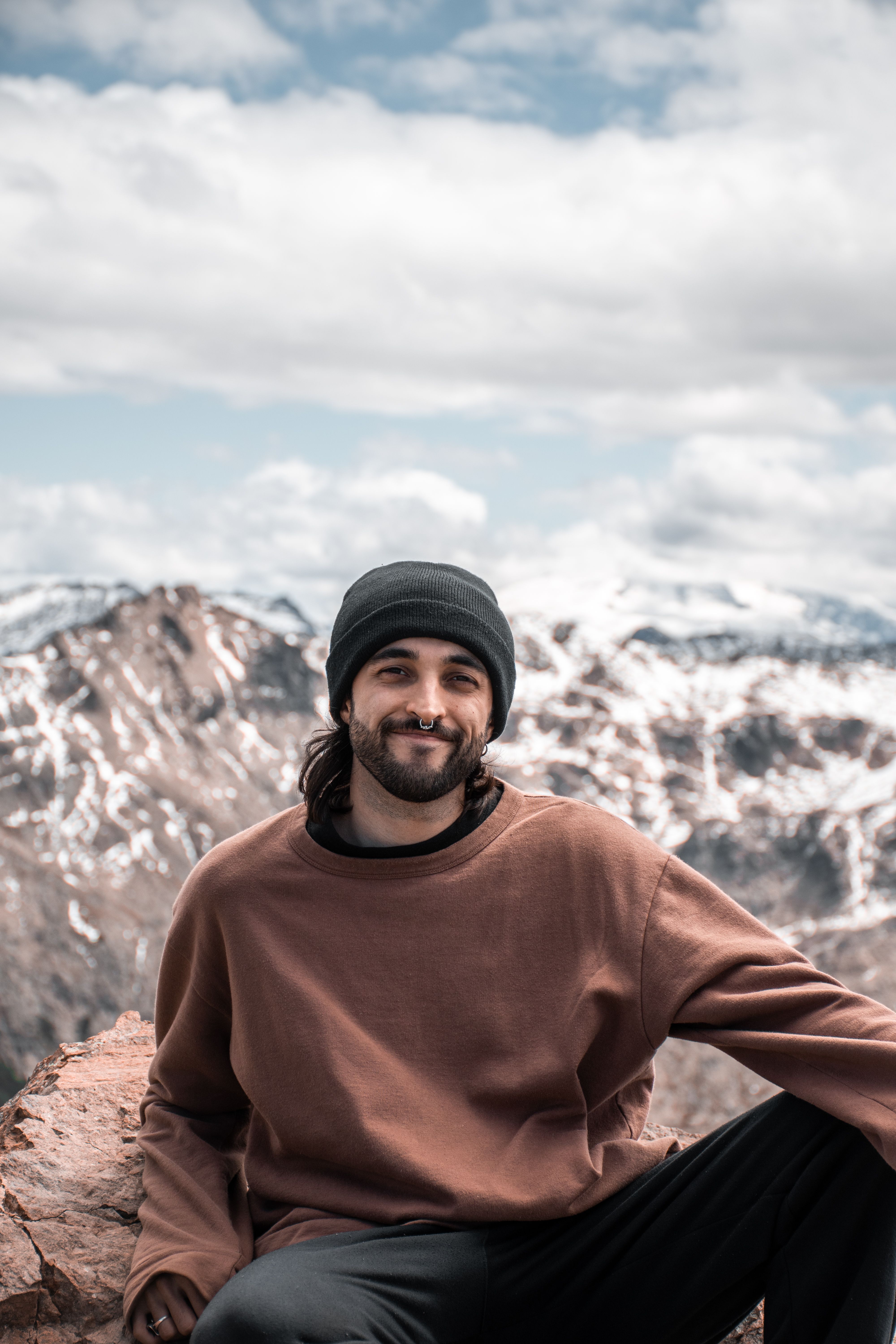 Smiling man sitting on rocks with snowy Patagonia mountains in the background.