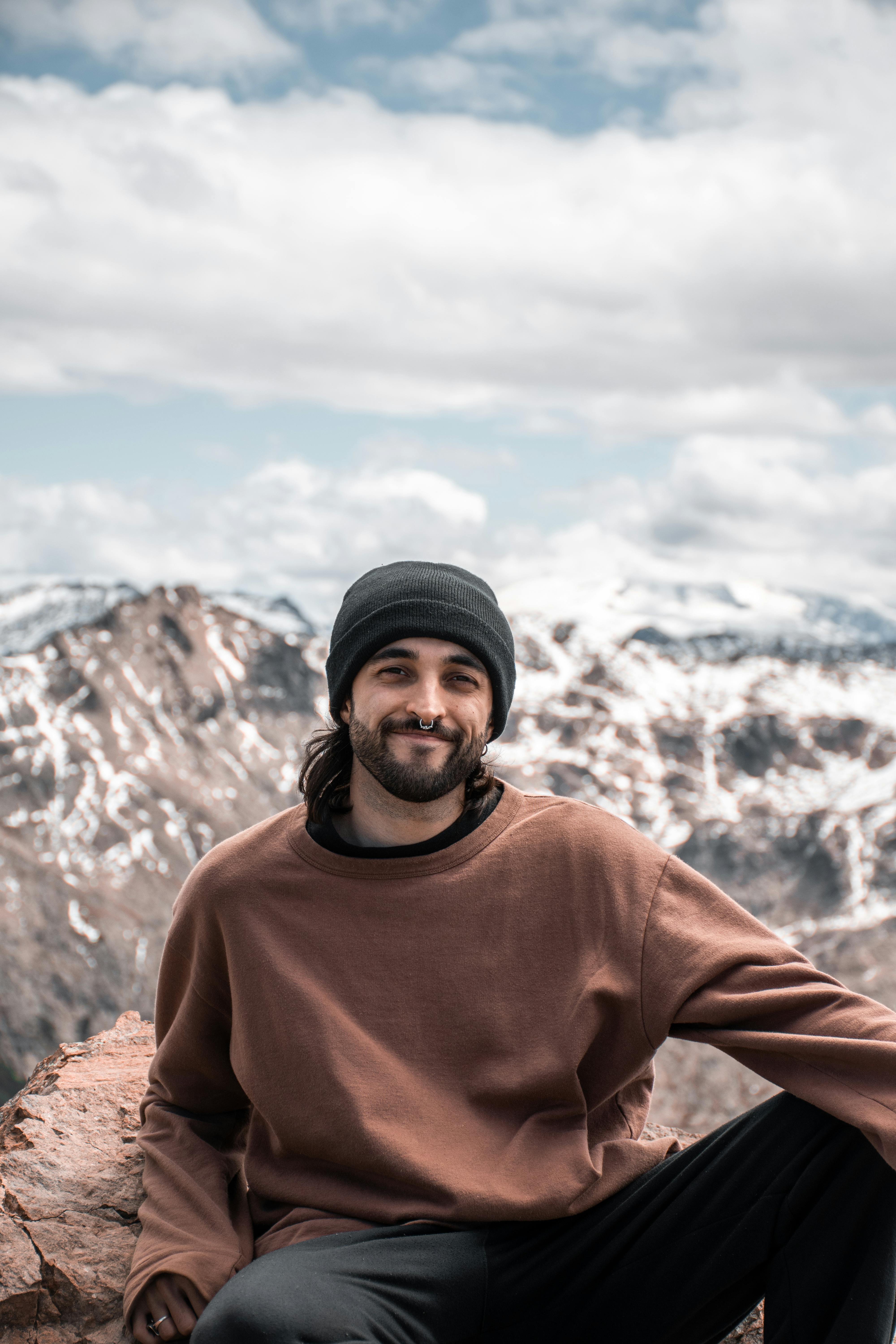 Free Smiling man sitting on rocks with snowy Patagonia mountains in the background. Stock Photo
