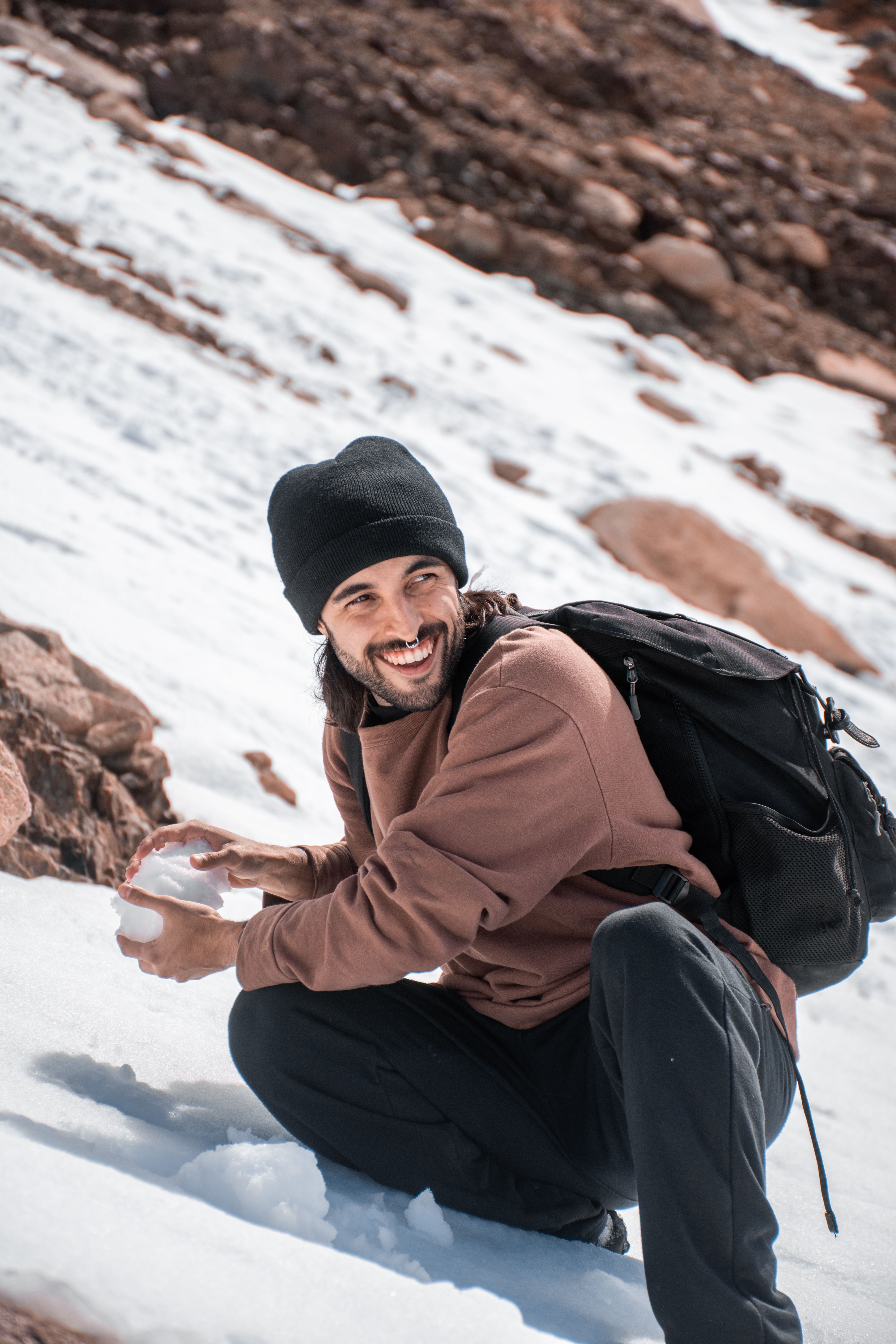 Adventurous man kneeling in snow with backpack, enjoying a winter trek in Patagonia. - Common Signs of Fake Shilajit