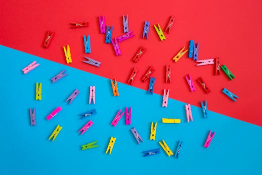 Colorful clothespins scattered on a contrasting red and blue background for a vibrant look.