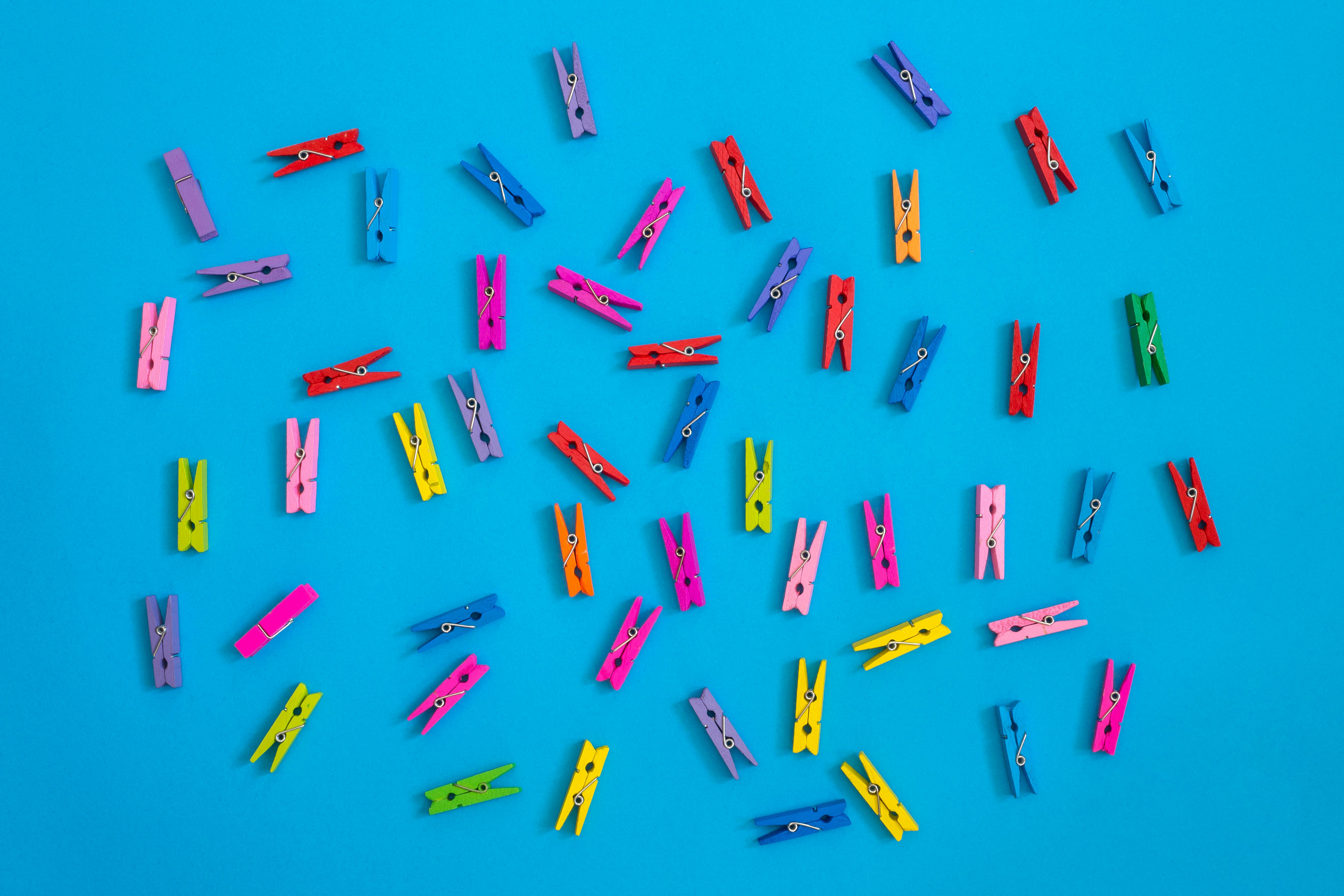Free Scattered colorful clothespins on a vivid blue background, top view. Stock Photo