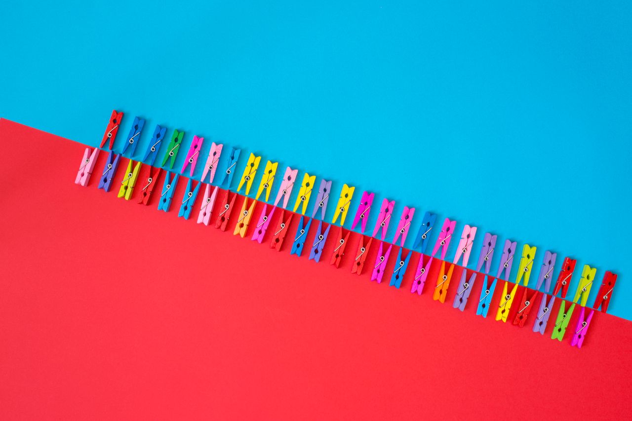 vibrant multicolored clothespins on a split red and blue surface creat