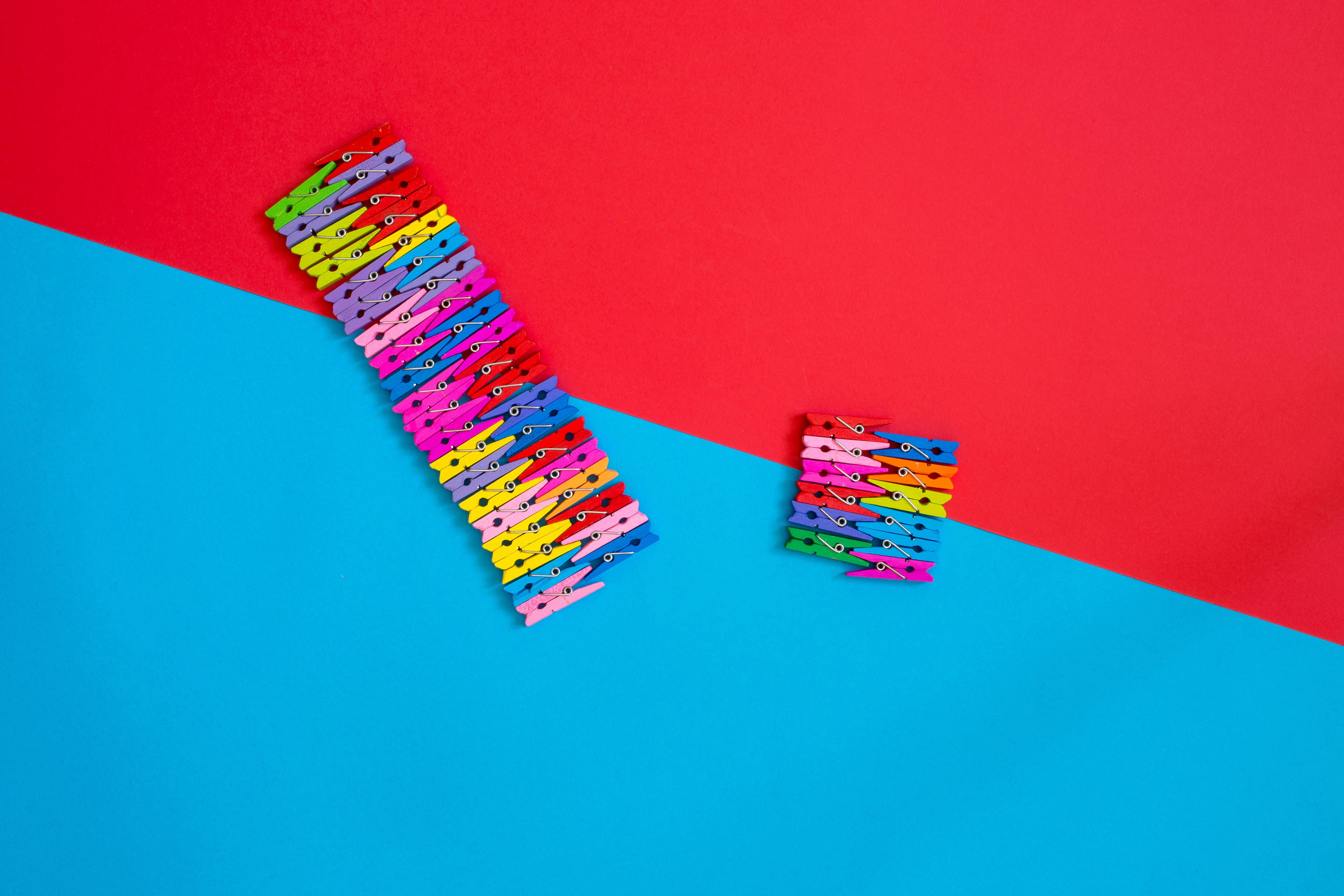 Bezpłatne Wielokolorowe klamerki ułożone kreatywnie na geometrycznym tle w kolorze czerwonym i niebieskim. Zdjęcie z galerii