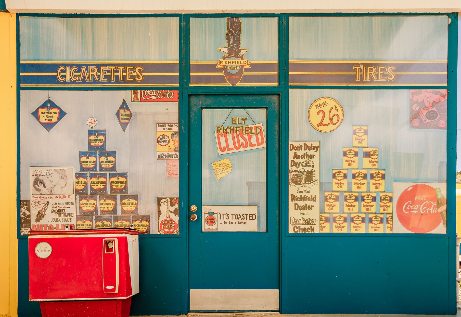 Classic mid-20th-century gas station storefront featuring vintage advertisements and signage.