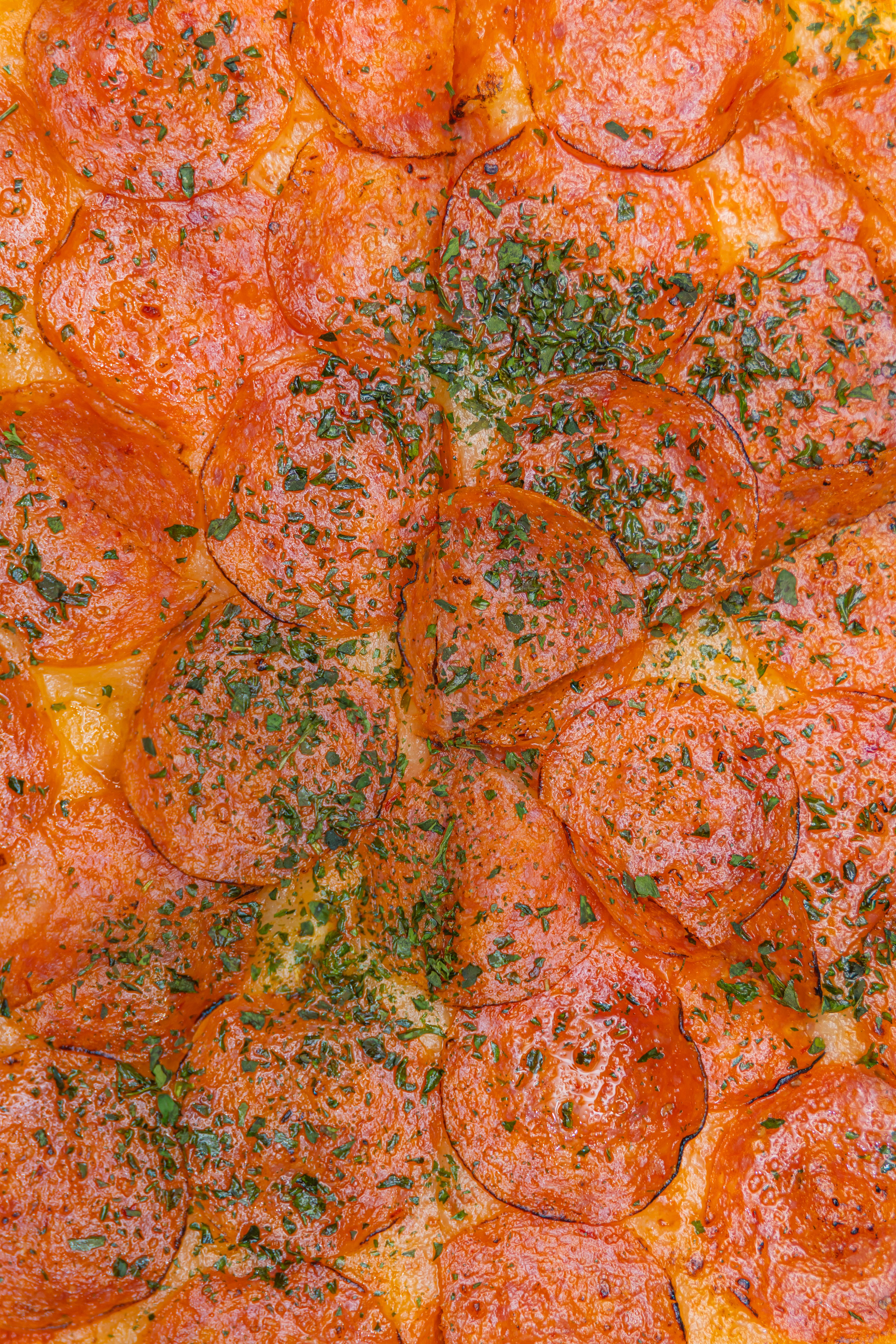A mouth-watering close-up of a pepperoni pizza topped with fresh herbs. Perfect for food enthusiasts.