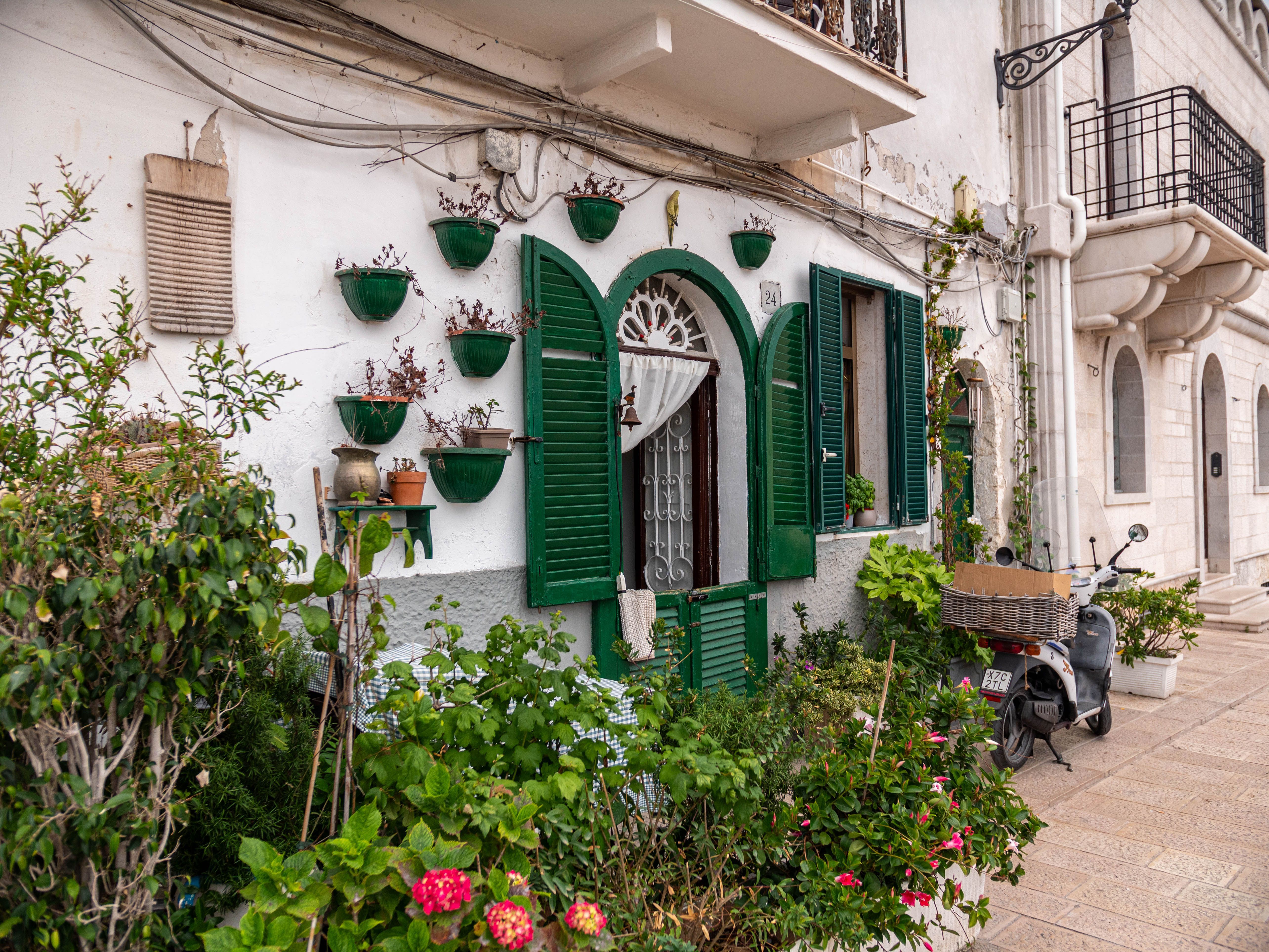 Classic Bari architecture with green shutters and lush plants, showcasing Apulian charm.