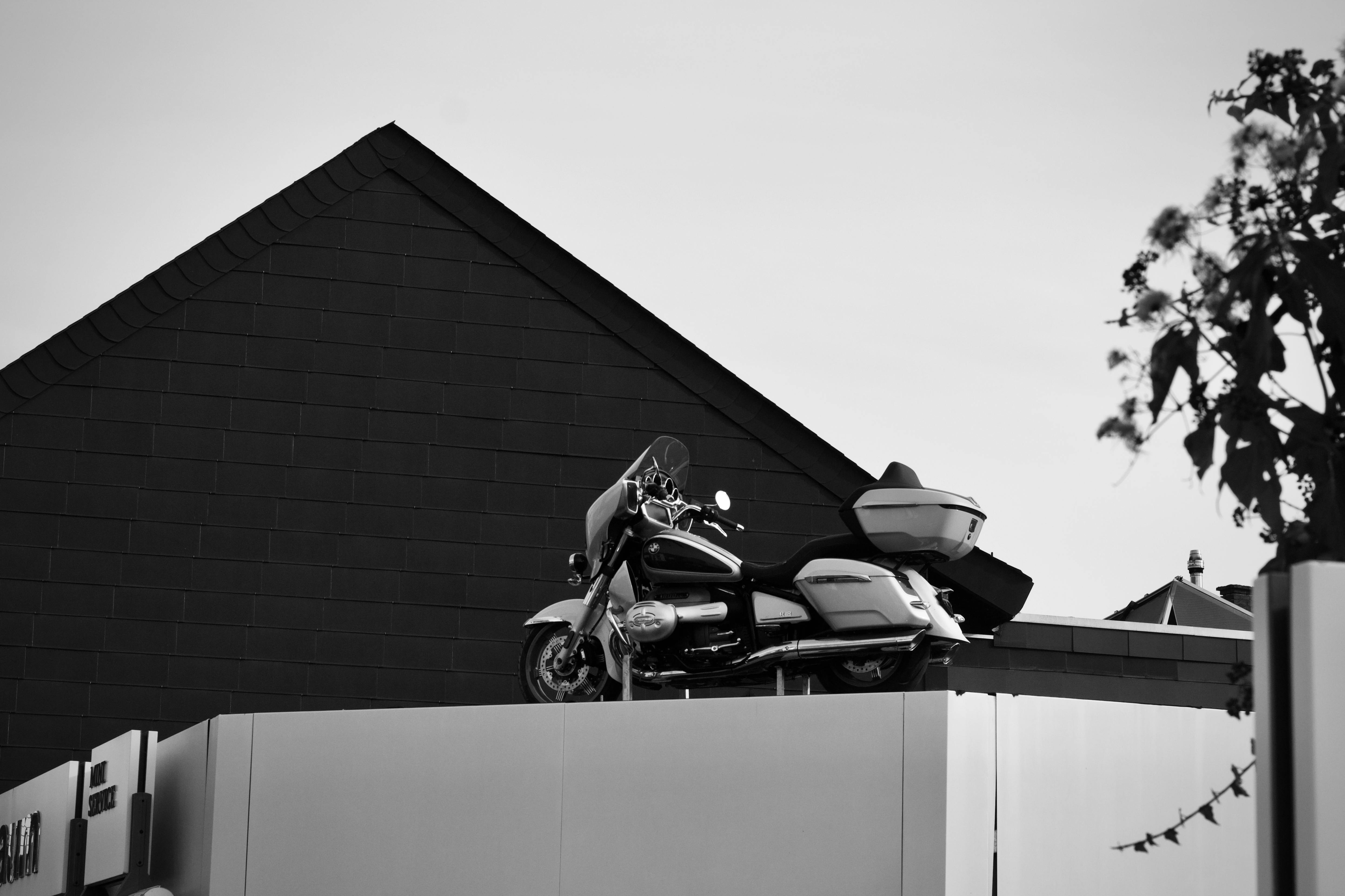 grátis Fotografia em preto e branco de uma motocicleta estacionada em um telhado com arquitetura moderna. Foto profissional