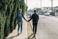 Man Holding Woman While Walking on Sidewalk