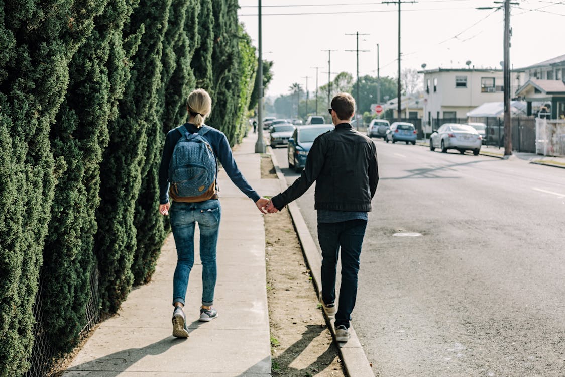 Free Man Holding Woman While Walking on Sidewalk Stock Photo