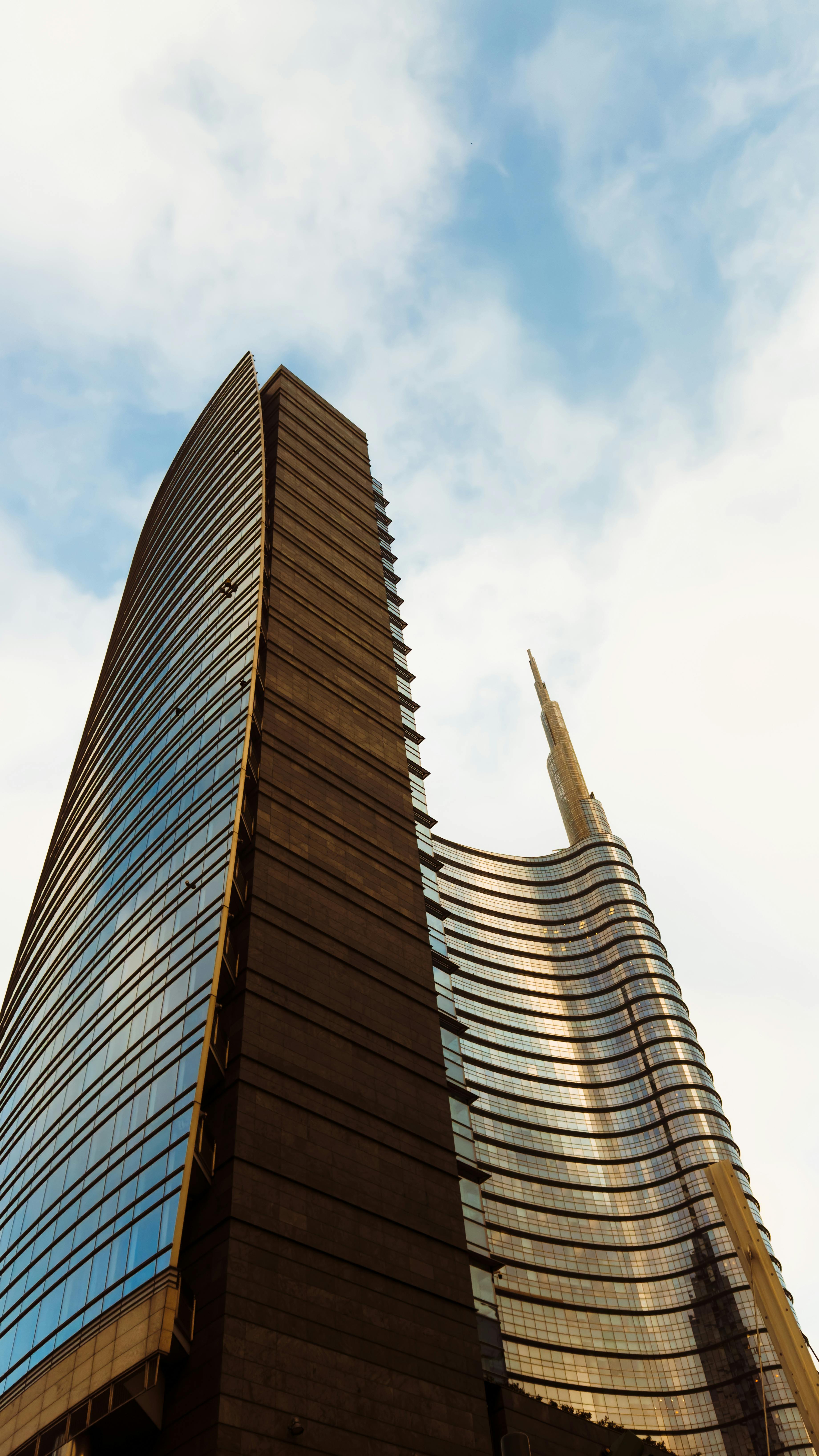 無料 青い空を背景に太陽光を反射し、建築の卓越性を示すミラノの近代的な高層ビルの素晴らしい眺め。 写真素材