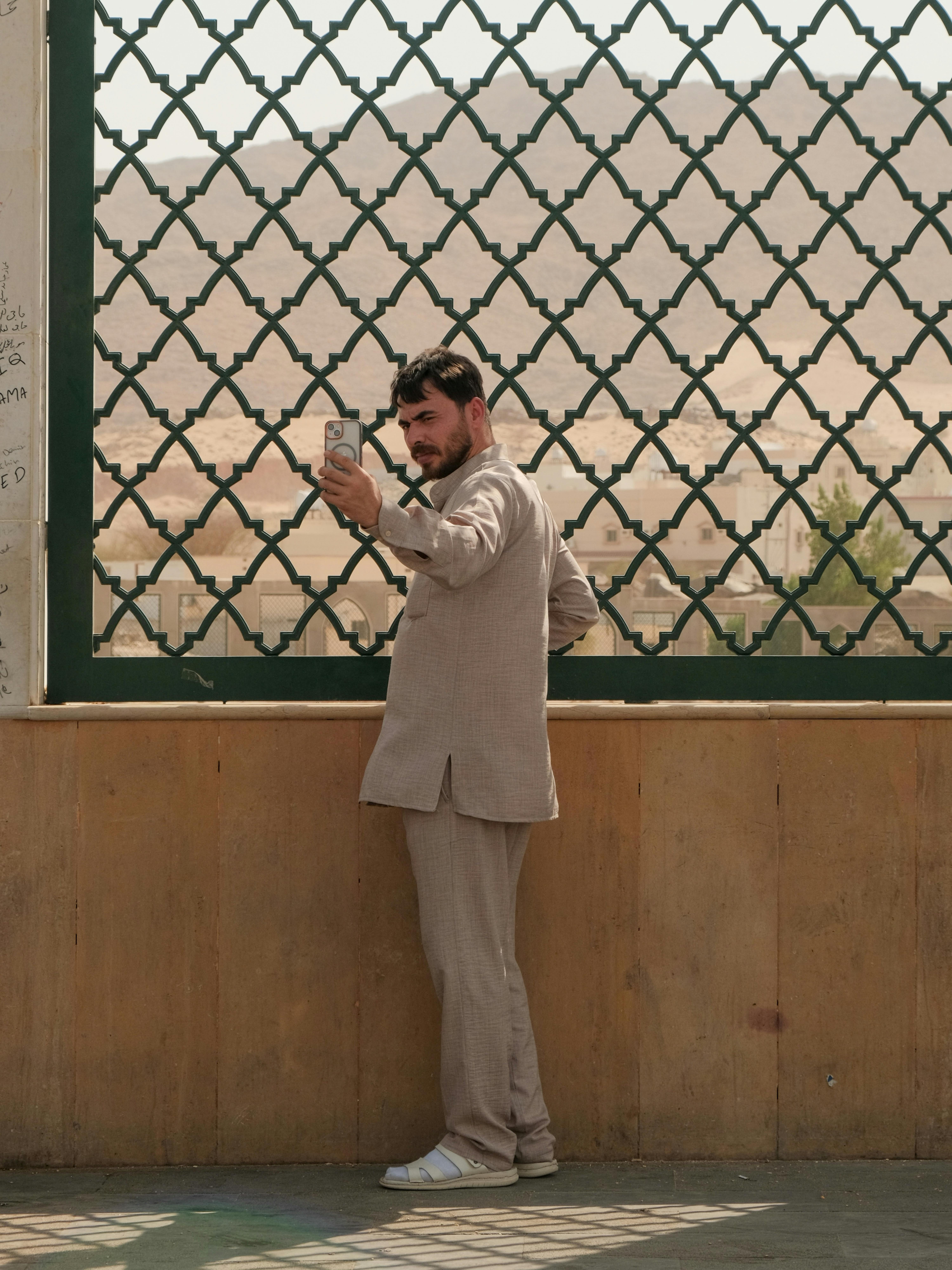 бесплатная Мужчина в традиционной одежде делает селфи на фоне пустыни в Саудовской Аравии. Стоковое фото