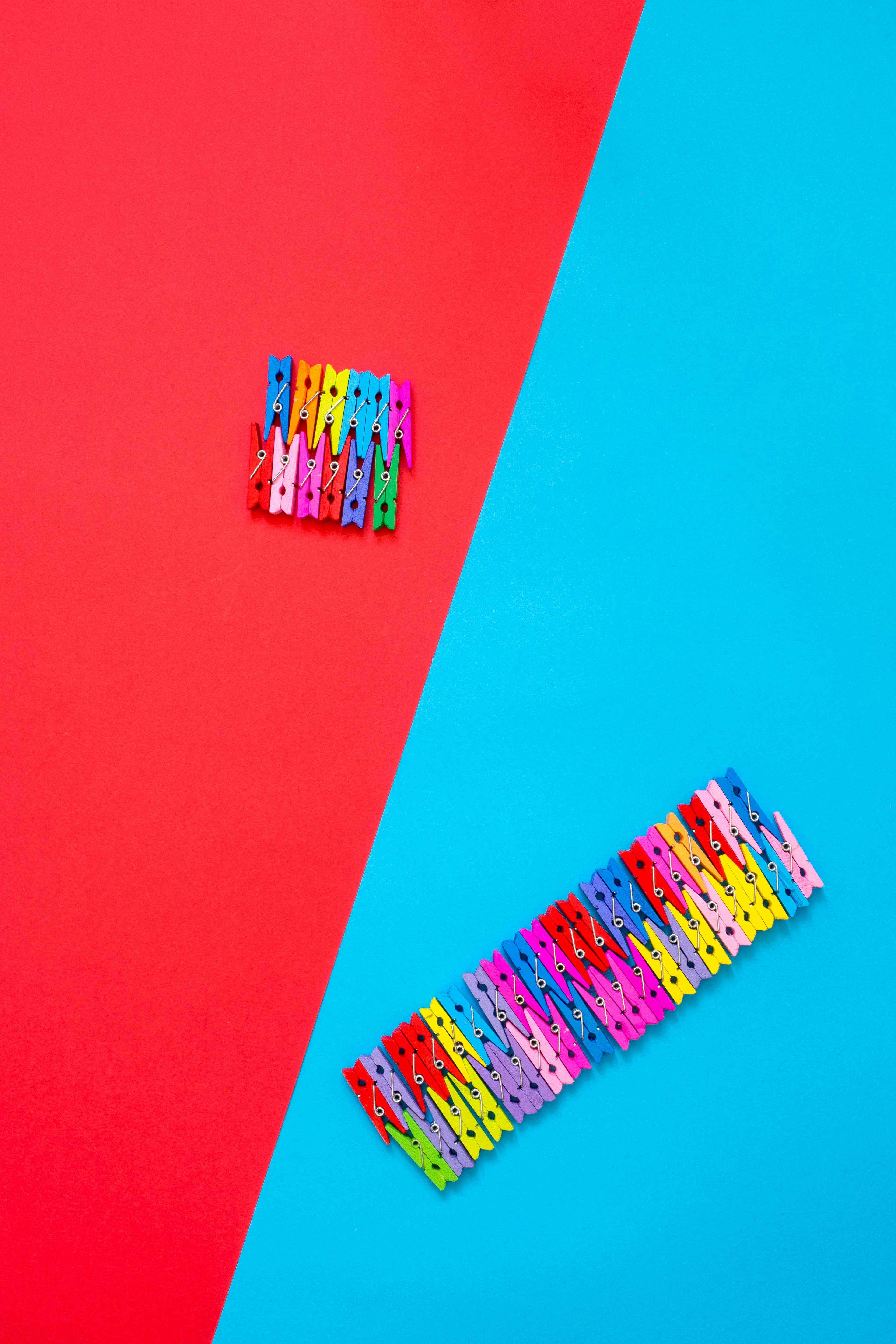 免費 鮮豔多彩的衣夾排列在對比鮮明的紅藍背景上，構成了一幅充滿活力和趣味的畫面。 圖庫相片