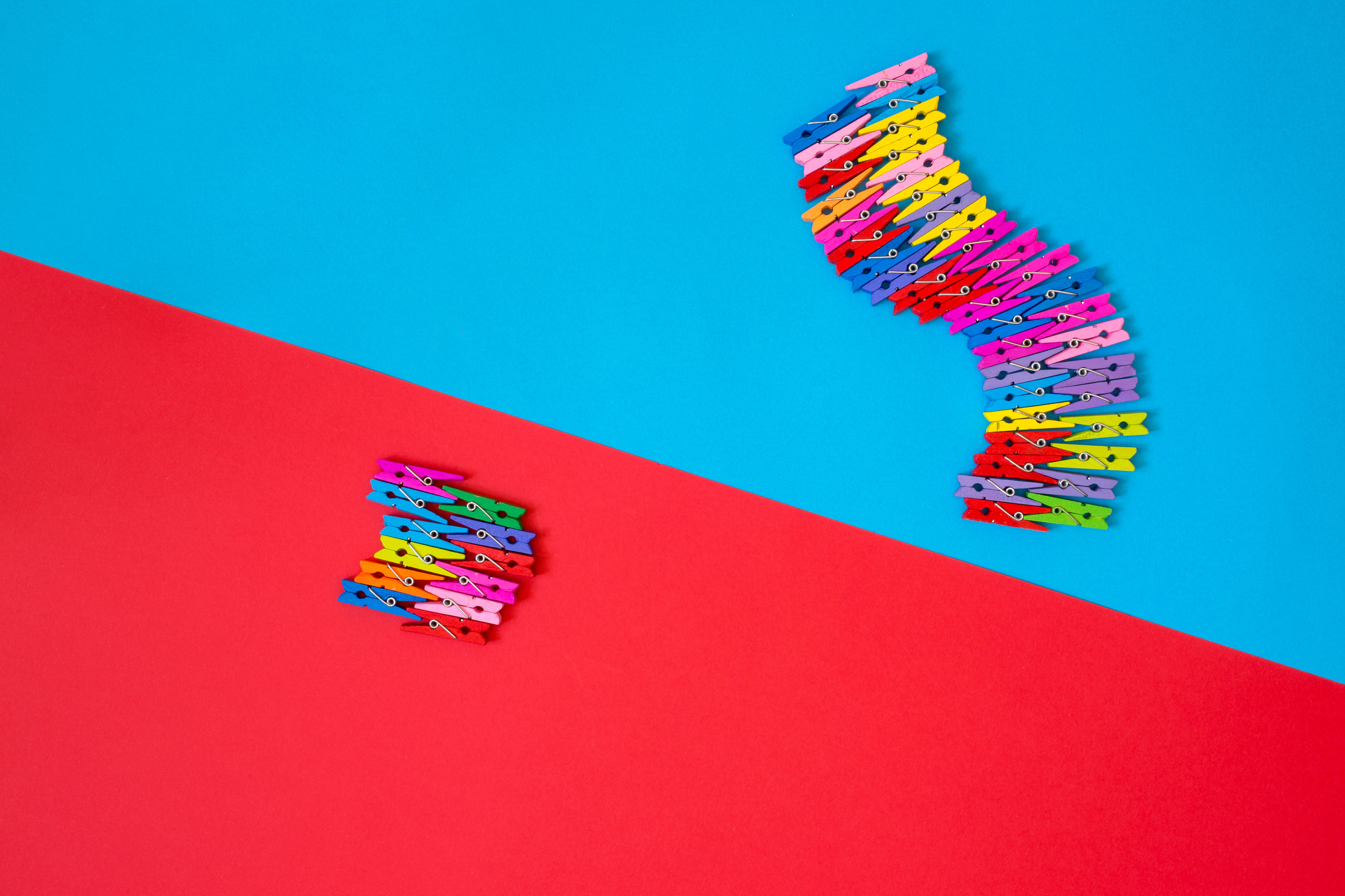 A creative arrangement of colorful clothespins on bright red and blue backgrounds.