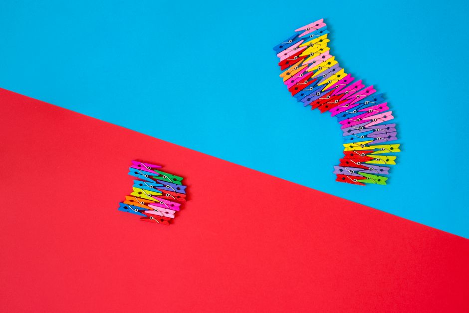 Como a Criatividade Pode Aumentar sua Autoestima Diariamente 2 A creative arrangement of colorful clothespins on bright red and blue backgrounds.