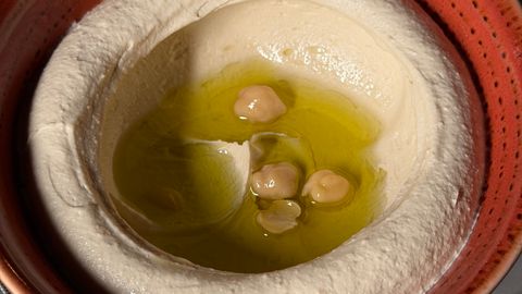 Delicious hummus dip garnished with olive oil and chickpeas.
