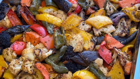 A vibrant tray of assorted roasted vegetables including cauliflower, peppers, and eggplant.