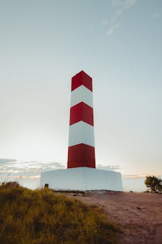 Red and white striped lighthouse in Bahia, Brazil during a clear day.