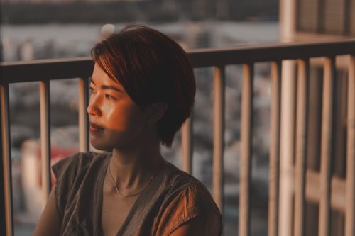 Free A woman gazing thoughtfully from a balcony at sunset in Ho Chi Minh City, Vietnam. Stock Photo