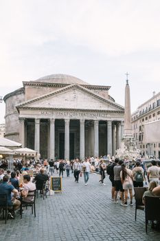 Bustling scene at Pantheon in Rome, Italy with tourists and outdoor cafes in Piazza della Rotonda.