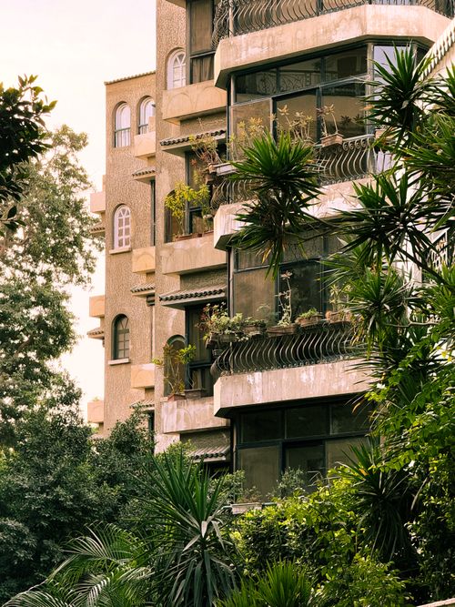 Free A distinctive urban apartment building adorned with lush balcony plants. Stock Photo