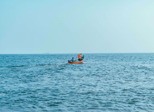 Free A colorful fishing boat sails on the tranquil ocean under a clear blue sky. Stock Photo