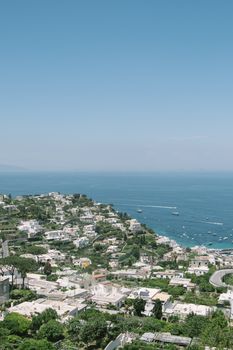 A breathtaking view of Capri's coastline, featuring lush greenery and the blue Mediterranean Sea.