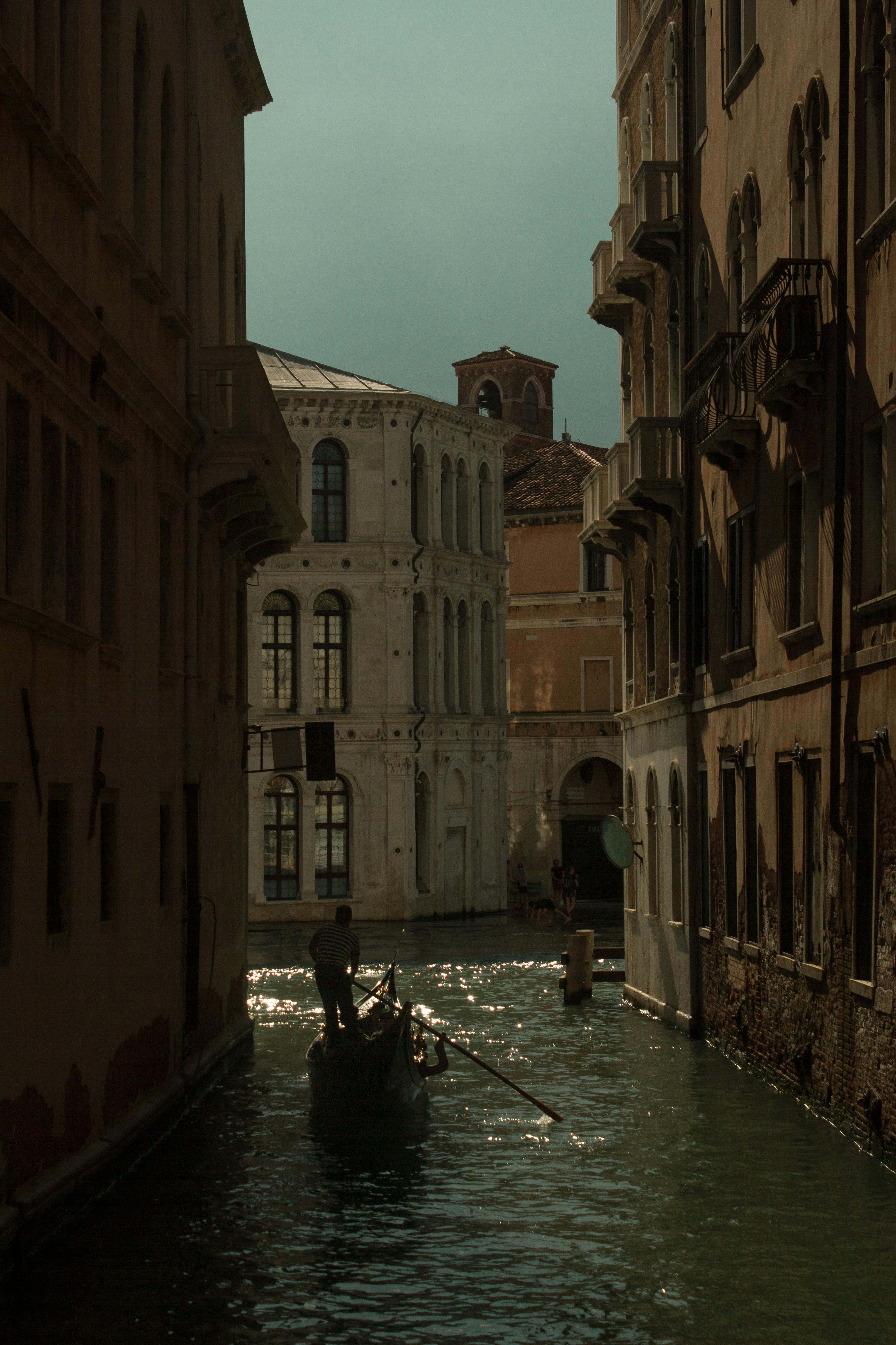 бесплатная Спокойная прогулка на гондоле по историческим каналам Венеции на закате на фоне старинной архитектуры. Стоковое фото
