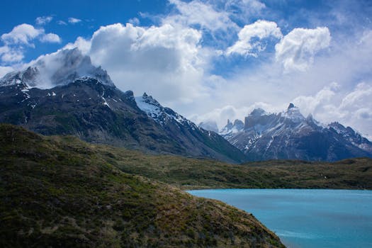 在多云的天空下，白雪皑皑的山脉和宁静的湖泊令人叹为观止