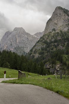 Breathtaking view of the Dolomite mountains with lush greenery and cloudy skies.