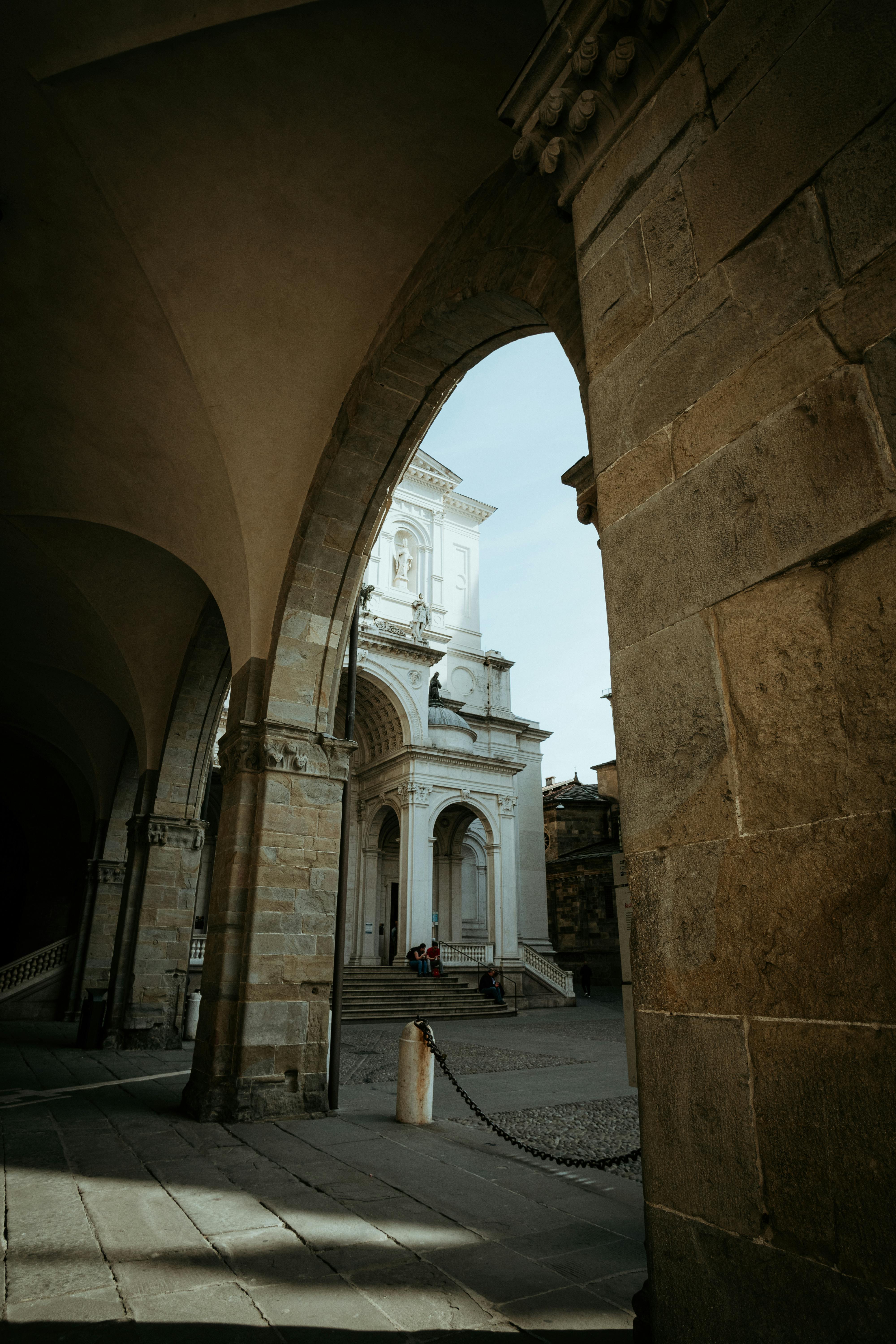 бесплатная Исторический собор в Италии, обрамленный арочной дорожкой, демонстрирует потрясающую архитектуру. Стоковое фото