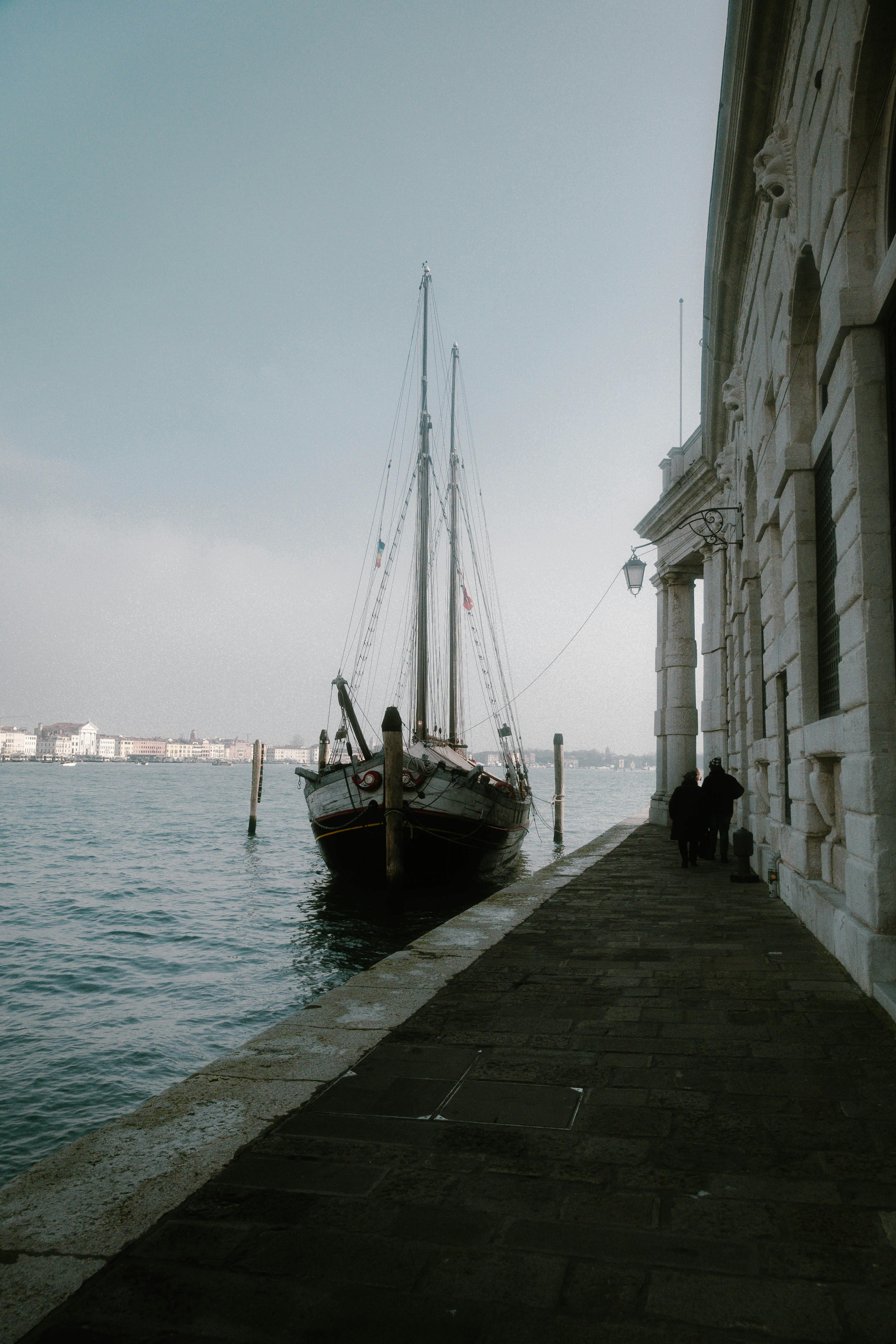 Ücretsiz İtalya'nın Venedik kentinde bir kanala demirlemiş eski bir yelkenli tekne, sakin bir sabah manzarasını yakalıyor. Stok Fotoğraflar