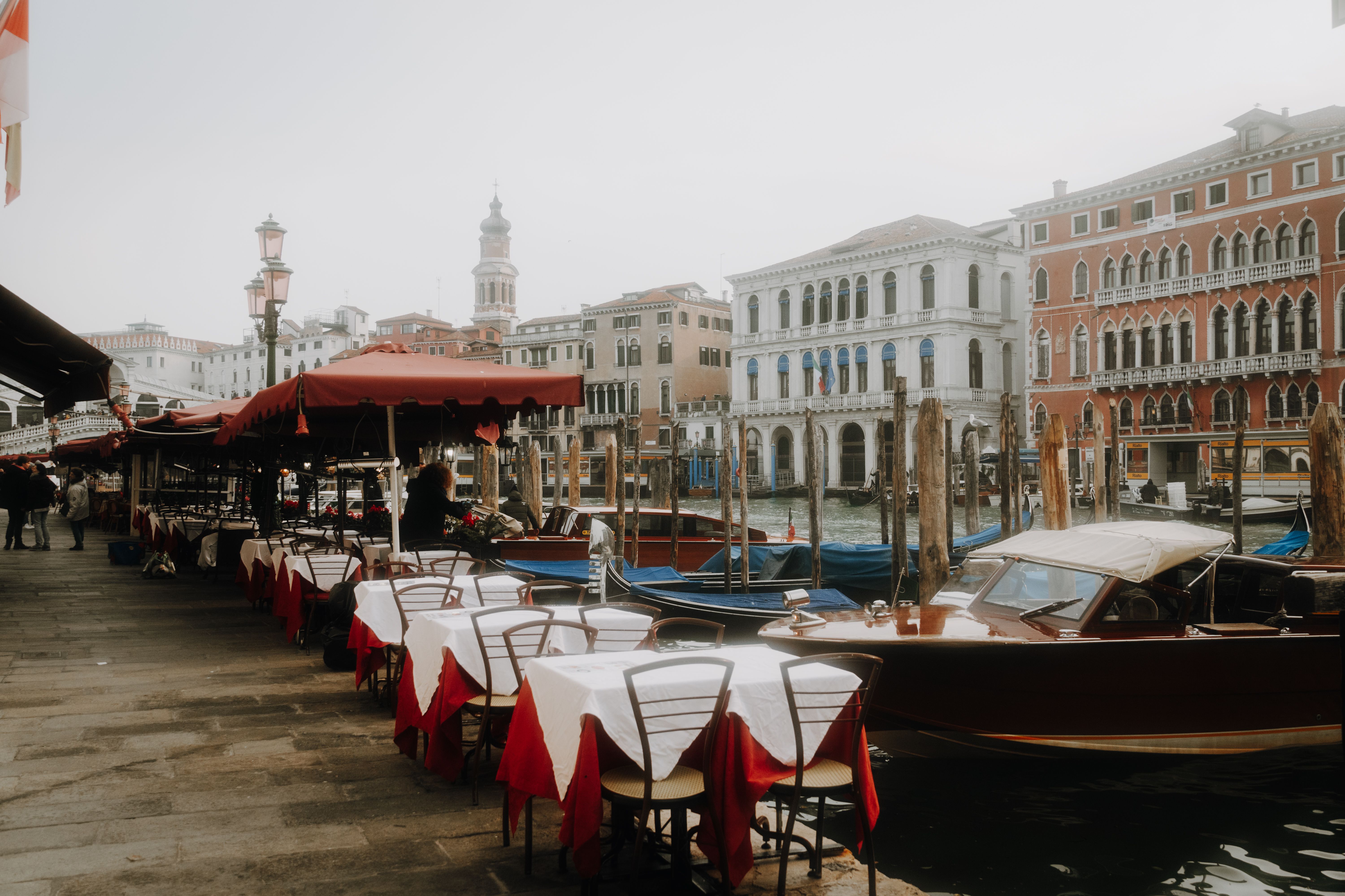 Idyllic Venice scene with canal, outdoor café seating, and classic Italian architecture.