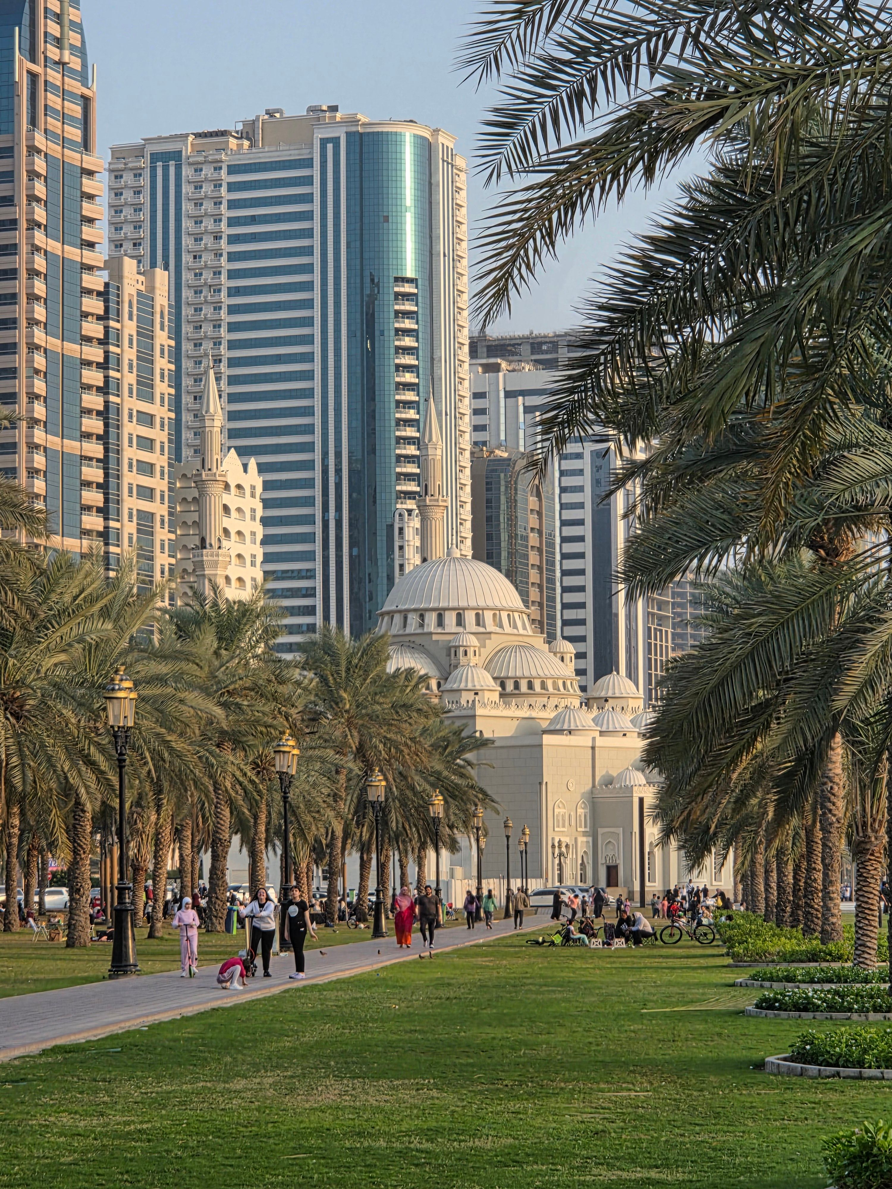 Stunning view of a mosque surrounded by skyscrapers and palm trees.