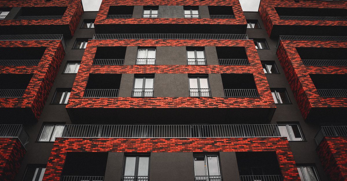 Low angle shot of a modern apartment building featuring a striking red brick facade design.