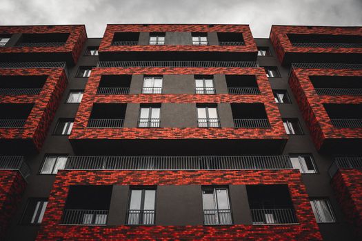 Low angle shot of a modern apartment building featuring a striking red brick facade design.