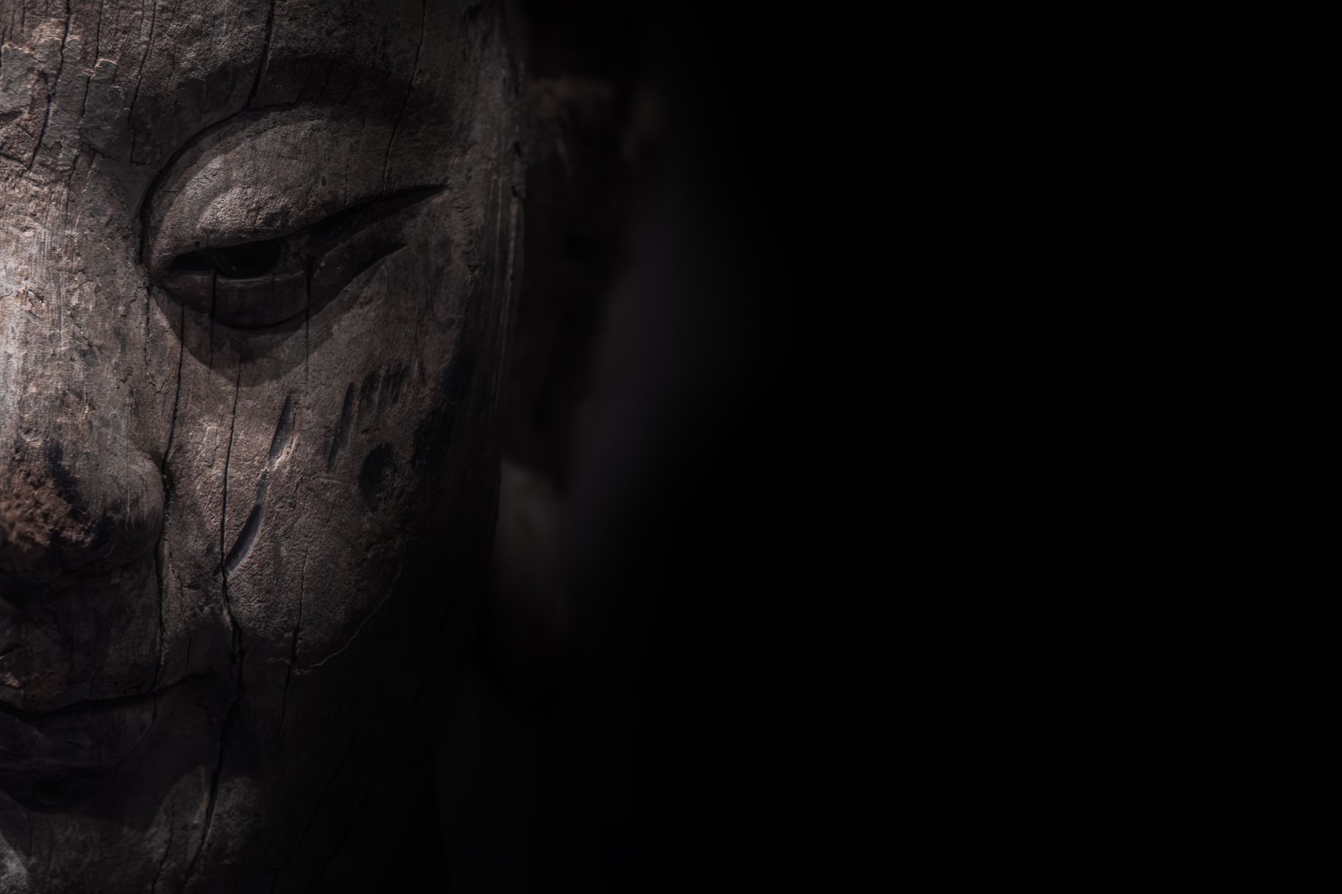 Detailed close-up of a textured wooden Buddha statue with dark, moody lighting. — Foto: zhou shen / Pexels
