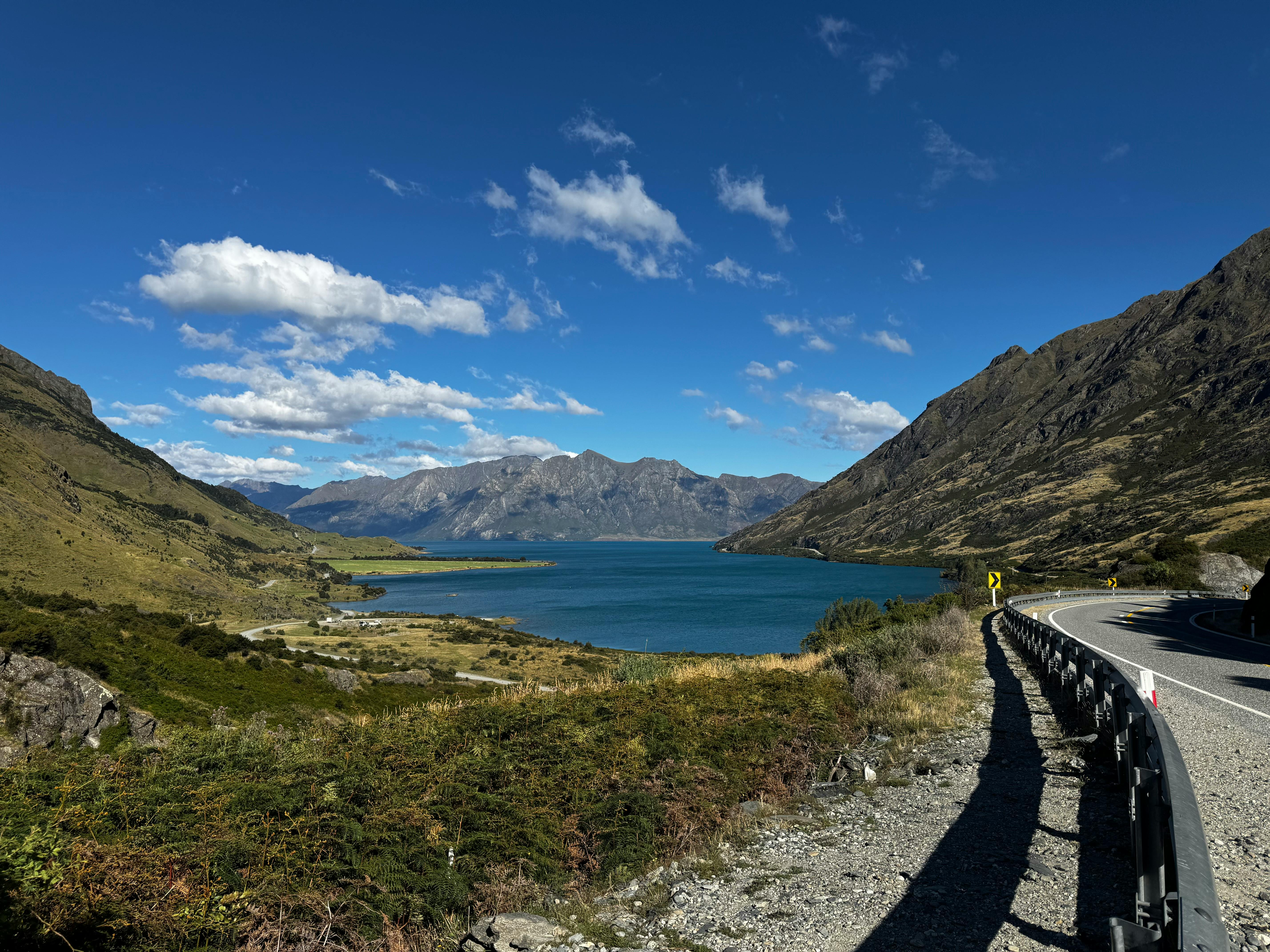 Serene landscape featuring Lake Hawea surrounded by mountains under a clear blue sky.