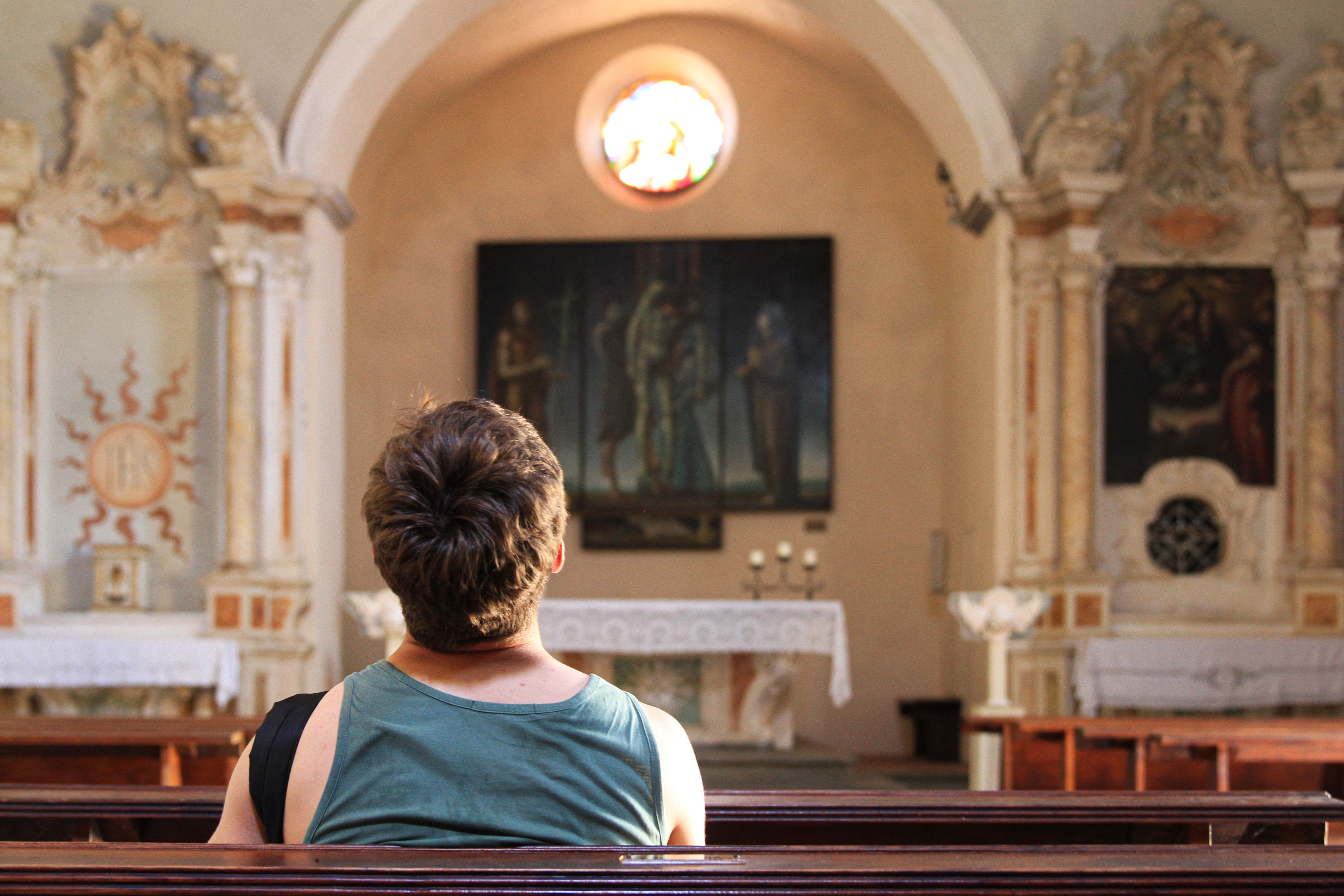 Free A person sits alone, reflecting in a beautifully decorated church interior. Stock Photo