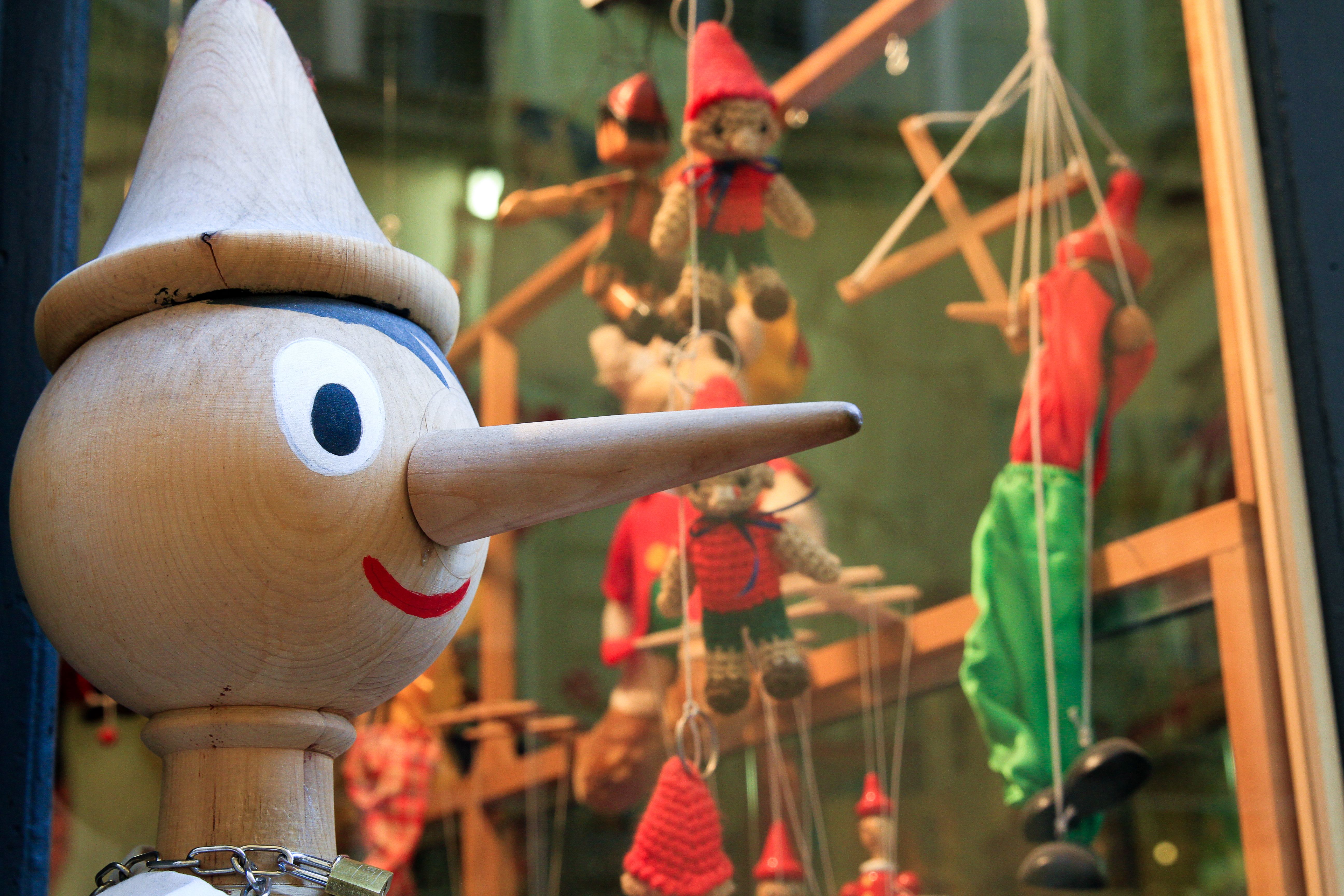 Free Wooden Pinocchio figure with puppets in a shop window display creates a whimsical scene. Stock Photo