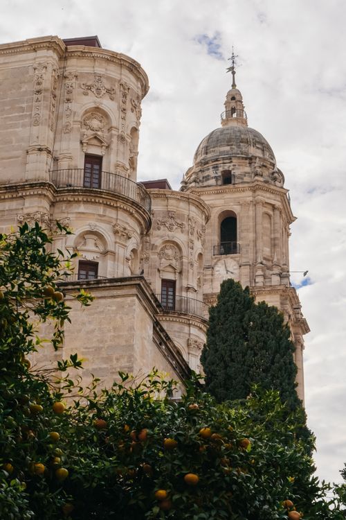 Free Ornate baroque cathedral with a domed tower and orange trees, set in a European cityscape. Stock Photo