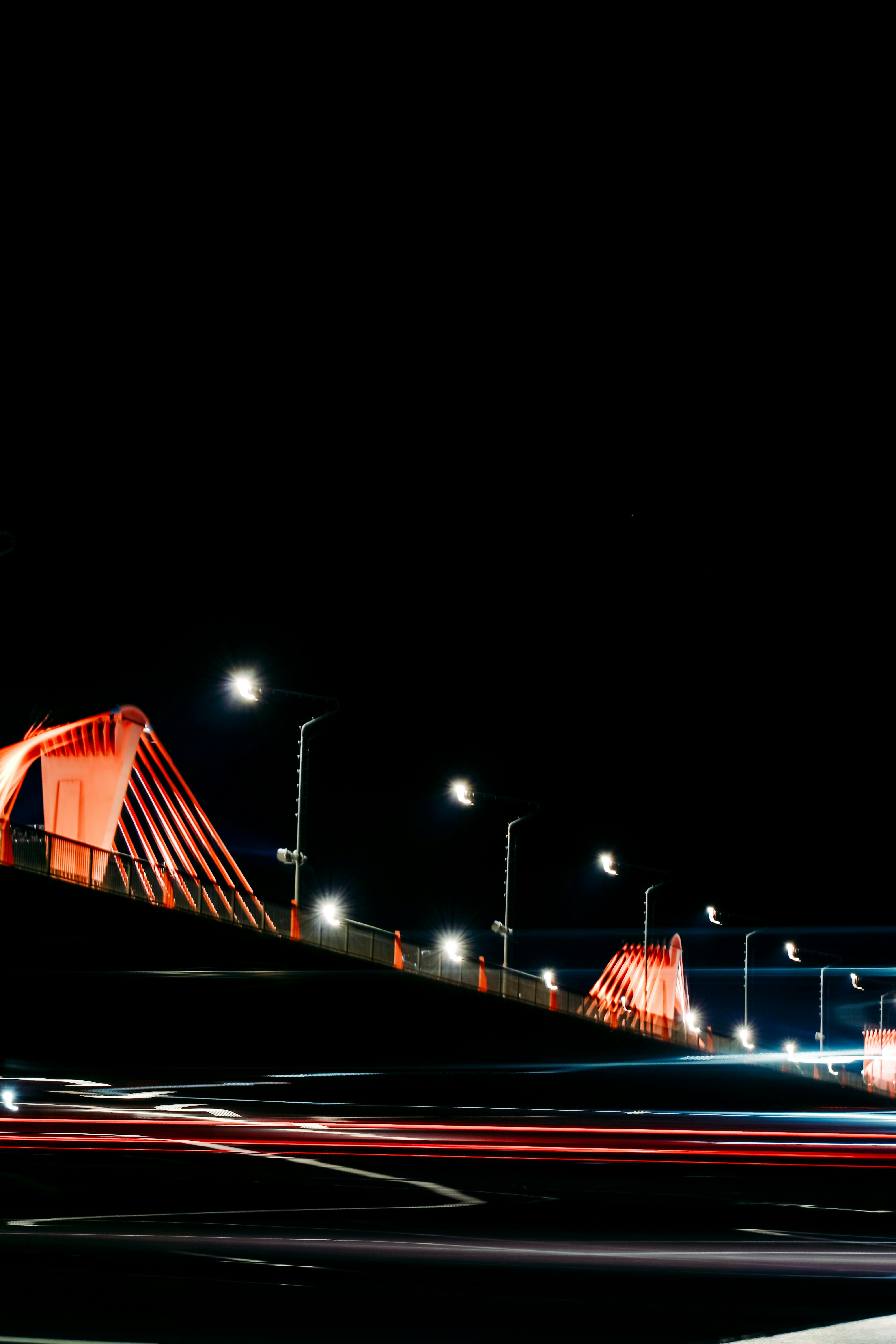 grátis Fotografia de longa exposição capturando o desfoque de movimento e as luzes da cidade em uma ponte em Riga à noite. Foto profissional