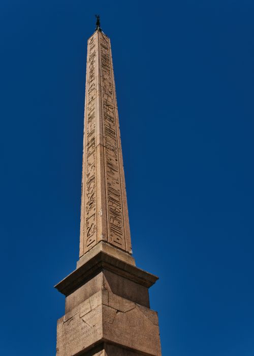 Free Tall ancient obelisk in Rome set against a clear blue sky, showcasing historical architecture. Stock Photo