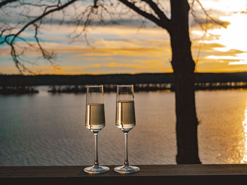 Elegant champagne glasses capturing a serene sunset by the lake