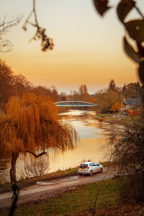 Free Sunset view of River Severn and bridge in Shrewsbury, England with warm sky and willow trees. Stock Photo